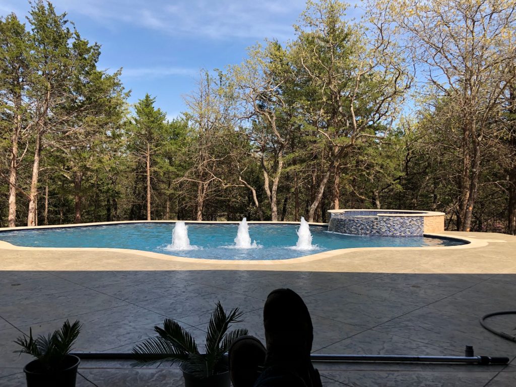 Freeform pool with raised spa and stamped concrete patio in The Falls Jones Oklahoma.