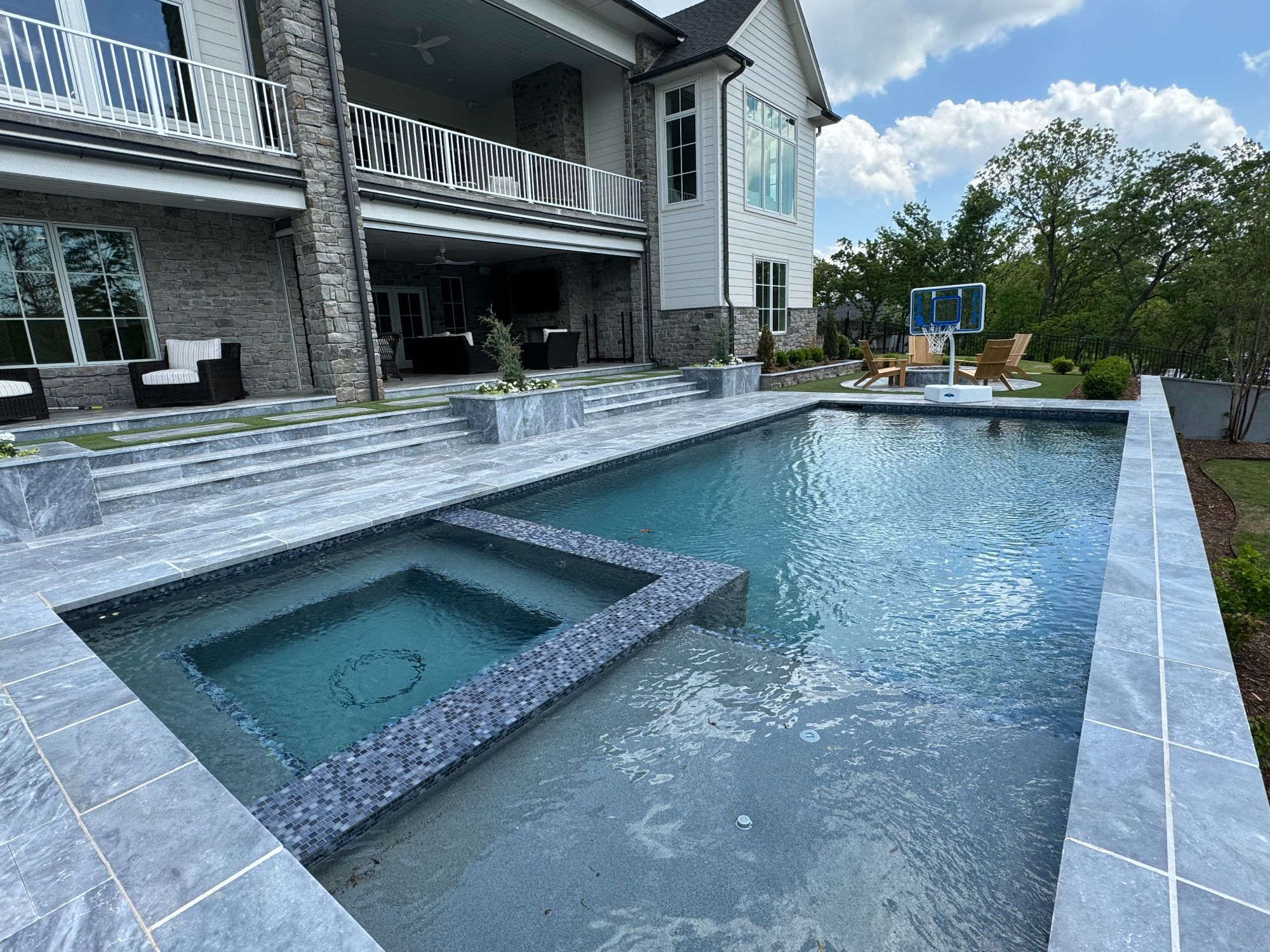 Flush spa integrated into geometric pool with Admix Blue mosaic tile and Ice Blue marble coping in Jones Oklahoma.