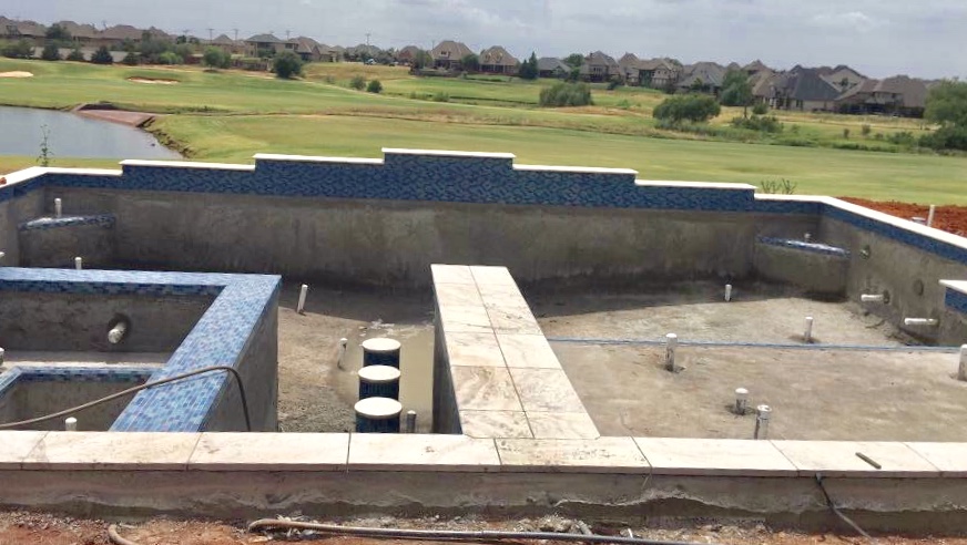 Geometric pool construction showing structural forming and plumbing before plaster in residential backyard.