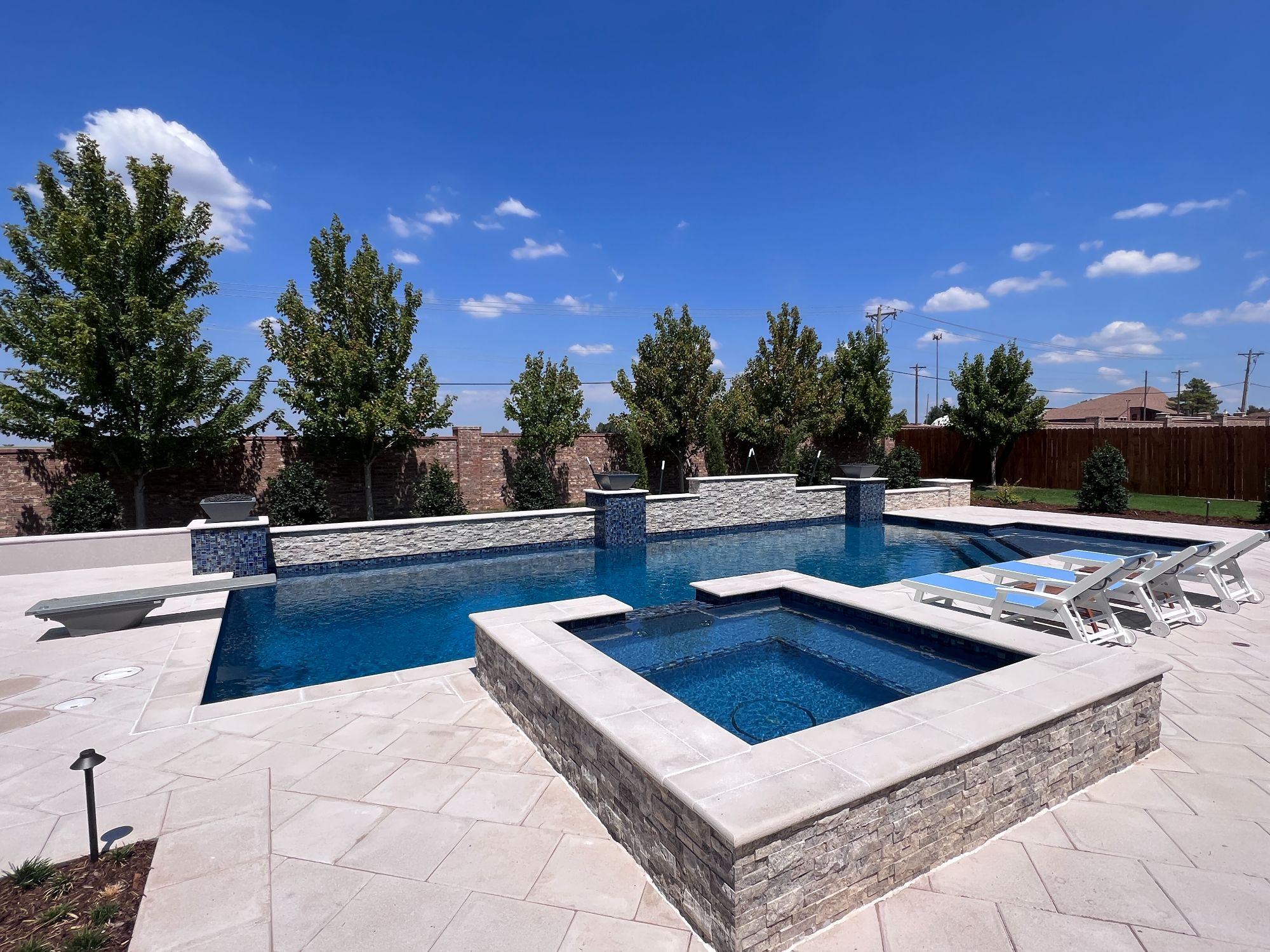 Geometric pool with raised spa and limestone paver deck in Oak Tree East Edmond Oklahoma.