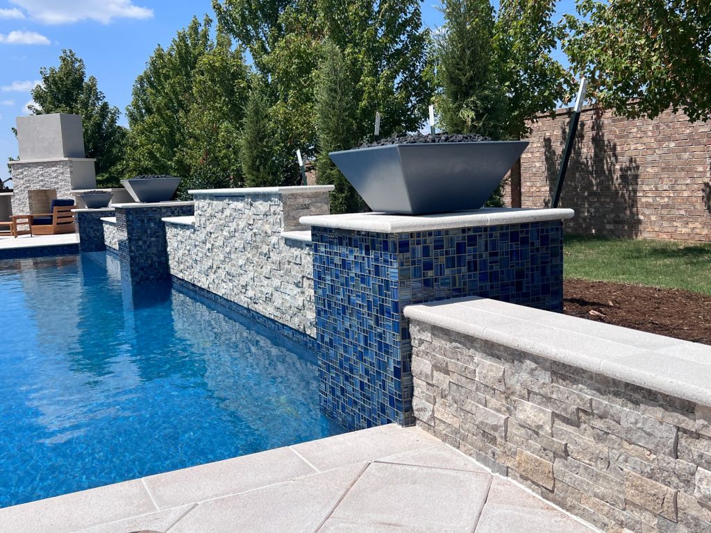 Raised wall with Silver split-face stone and fire bowl feature overlooking geometric pool in Edmond Oklahoma.