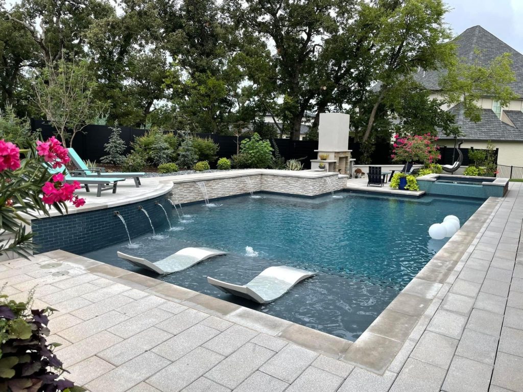 Tanning ledge with in-water loungers in custom geometric pool in Oak Tree East Edmond Oklahoma.