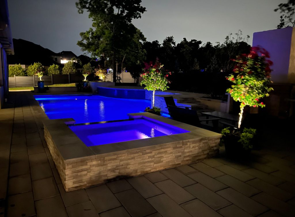 Night view of raised spa with blue LED lighting and geometric pool in Oak Tree East Edmond Oklahoma.
