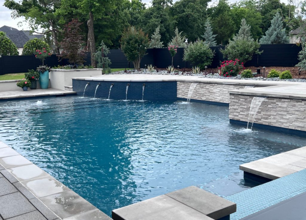 Raised stone wall with sheer descent water features and geometric pool in Oak Tree East Edmond Oklahoma.