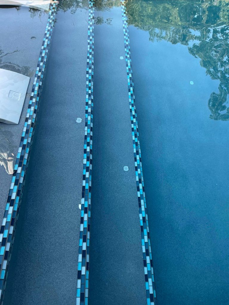 Pool step markers with Crystal Series Aqua Blend tile in Midnight Blue ecoFINISH geometric pool in Oak Tree East Edmond Oklahoma.